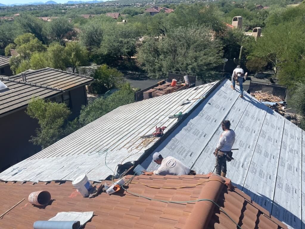 A team of roofing contractors is completing a new roof installation on a home in Tucson
